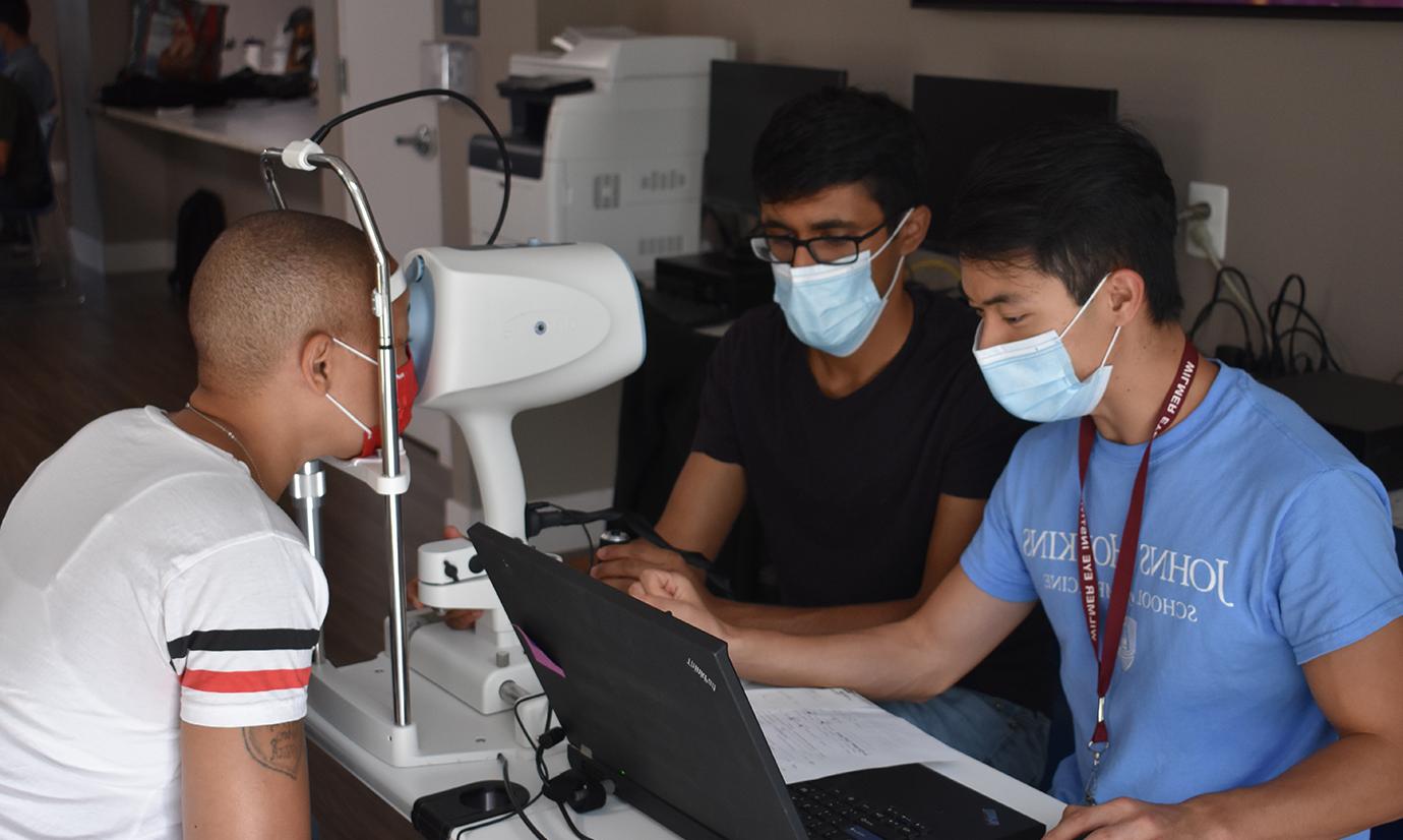 From left, Andrew Nguyen and Siddharth Venkatraman screen a patient at the optical coherence tomography (OCT) station.
